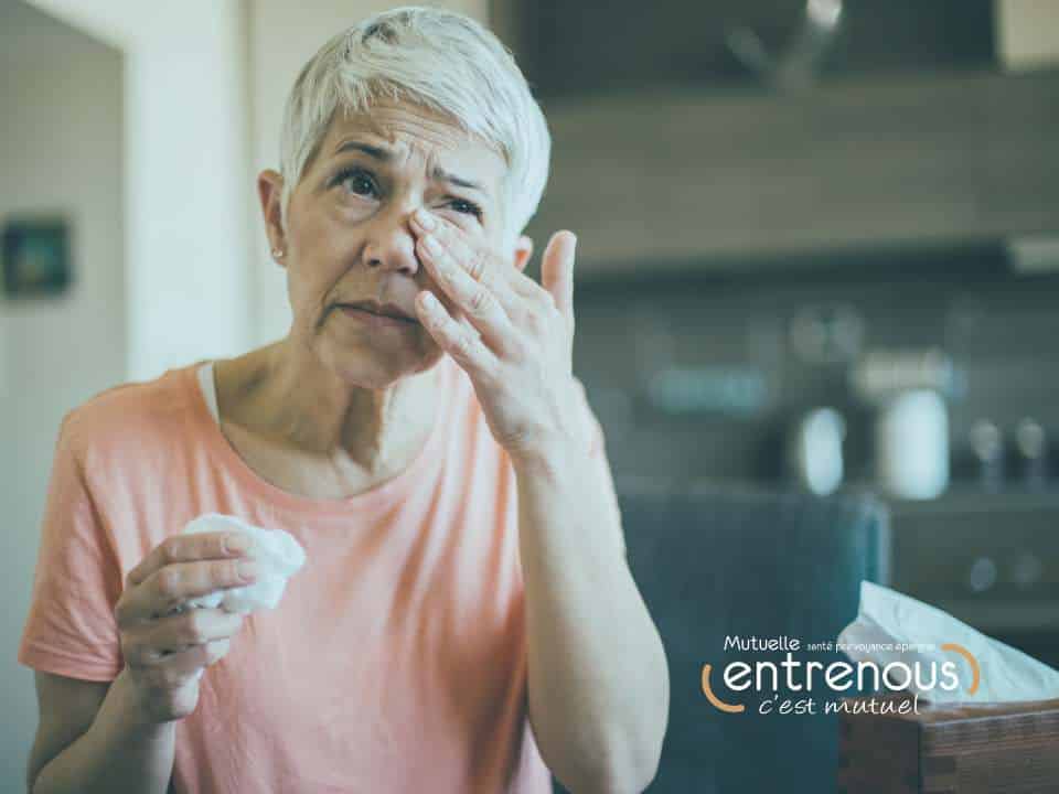 femme avec le rhume des foins qui se gratte les yeux et tient un mouchoir